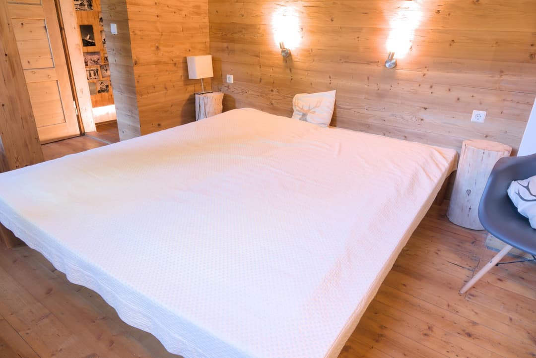 Großes Doppelbett mit weißem Bezug in Schlafzimmer mit Holz