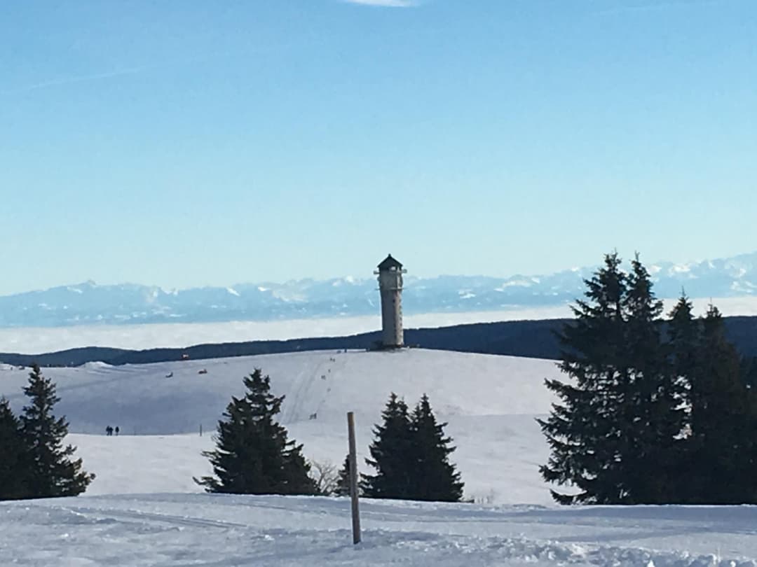 Blick auf einen Turm auf dem Feldberg im Winter mit blauem Himmel