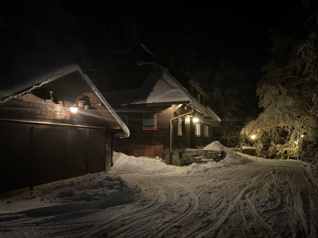 Rückansicht der Holzhütte im Winter mit viel Schnee im Dunkeln