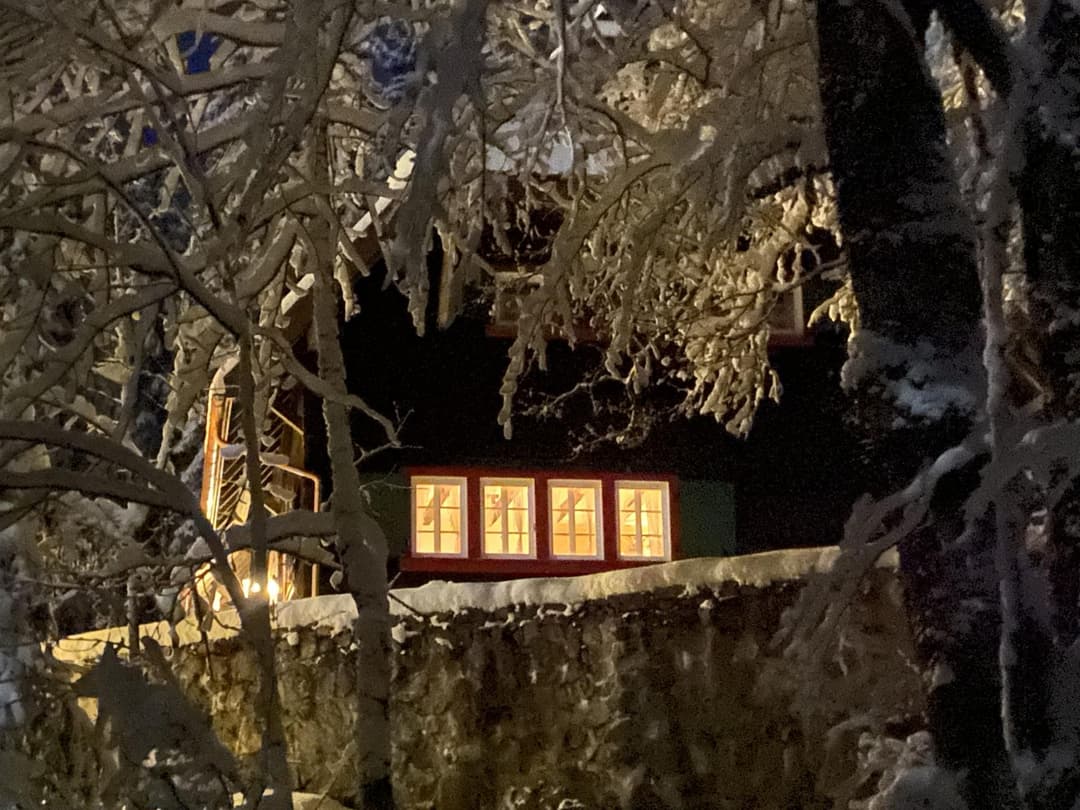 Gezoomte Frontansicht der Holzhütte mit viel Schnee im Dunkeln