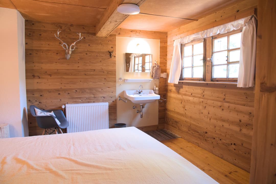 Waschbecken im Schlafzimmer mit Fenster und Bett im Vordergrund
